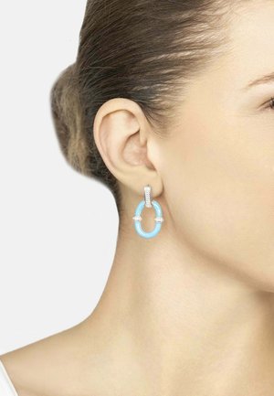 Light blue resin hoop earrings with silver accents and sparkling details, displayed on an ear against a neutral background.