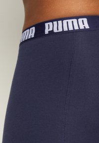 Navy blue athletic shorts with a smooth texture, featuring a white "PUMA" logo on the elastic waistband. Clean seams and a fitted design.