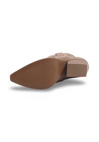 Dessous de chaussure en daim marron avec un embout pointu, un talon rectangulaire et une semelle extérieure en caoutchouc texturé comportant des rainures horizontales pour une meilleure adhérence.