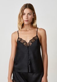 Camisole en satin noir avec des bretelles réglables, bordure en dentelle le long de l'encolure et détails de boutons sur le devant. Texture douce et design ajusté.