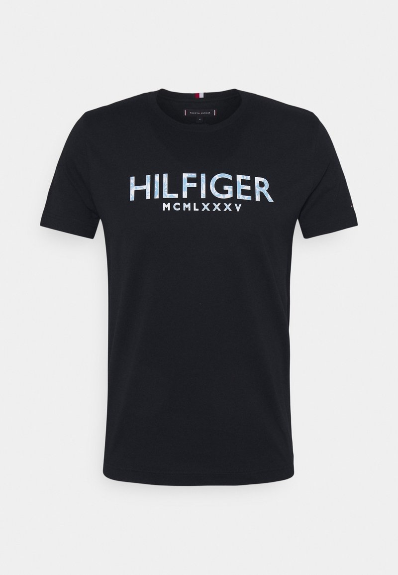 Mustat lyhythihaiset T-paidat, joissa on rintaosassa sinisellä ja valkoisella painettuna "HILFIGER MCMLXXXV".