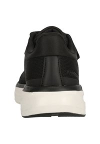 Schwarzer Sportschuh mit einer strukturierten Stoffoberfläche, geschwungener Rückendesign, gepolsterter weißer Außensohle und minimalem Branding an der Ferse.