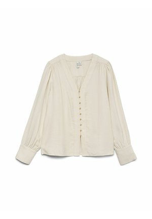 Blouse crème à manches longues avec décolleté en V profond, petits boutons sur le devant, épaules froncées et larges poignets sur fond blanc.