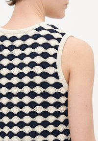 Strikket tanktop med bølgedesign i marineblå og kremfarger, rund halslinning og ermeløs design. Teksturert stoff synlig.