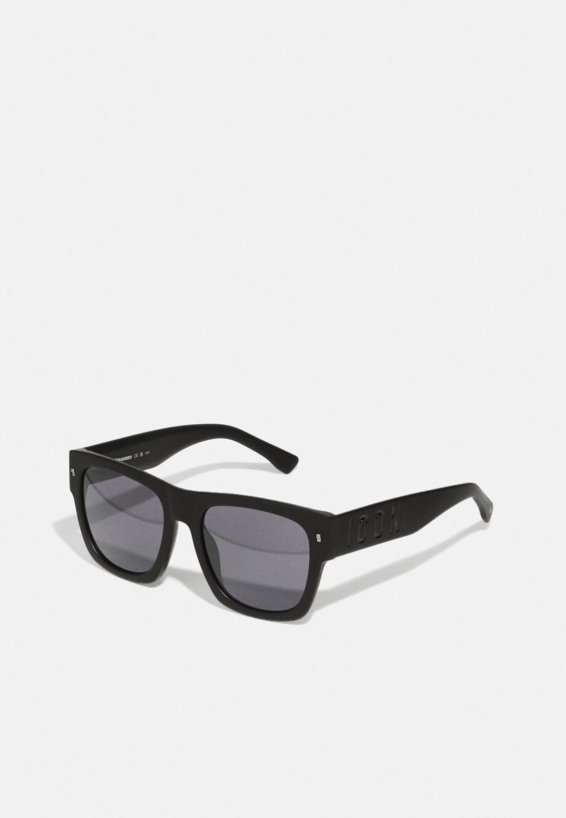 Occhiali da sole neri a forma rettangolare con lenti scure, finitura opaca e un branding discreto sulle astine. Montatura in plastica resistente.