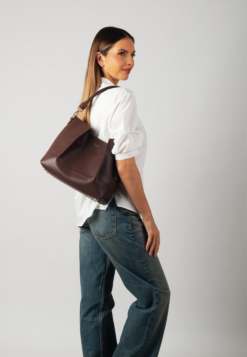 Borsa tote in pelle marrone con design strutturato, dotata di un pannello anteriore curvo, tracolla regolabile e dettagli di cucitura discreti.
