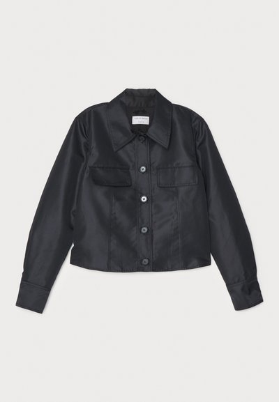 Črna satenska jakna z ovratnikom, sprednjim gumbnim zapiranjem, dvema prsoma žepoma in dolgimi rokavi z gumbnimi manšetami.