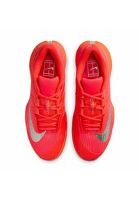 Helle rote Sportschuhe mit silbernen Nike-Swooshes, Schnürdesign und gepolsterten Kragen, aus einer Draufsicht gezeigt.