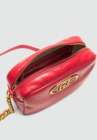 Rote Leder-Crossbody-Tasche mit strukturiertem Finish, goldenen Beschlägen und einem Reißverschlussverschluss. Das Innere verfügt über ein beiges Futter mit Logodetail.