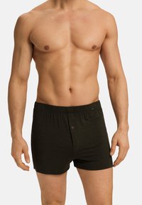 Tmavě zelené bavlněné boxerky s elastickým pasem a jedním knoflíkem, dobře přiléhající k pasu modelu.