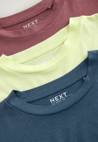 Drei zusammengefaltete T-Shirts mit Rundhalsausschnitt in Burgunderrot, Blassgelb und Marineblau, mit sichtbaren "NEXT" Markenetiketten im Kragen.