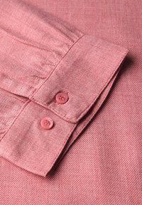 Camicia in cotone rosa con finitura testurizzata, dotata di colletto button-down e due bottoni rosa abbinati sui polsini.