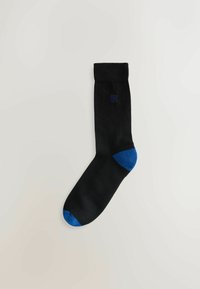 Schwarze Socke mit blauem Zehen- und Fersenakzent. Glatte Textur und gerippter Bund. Verfügt über ein kleines blaues Logo nahe dem oberen Rand.