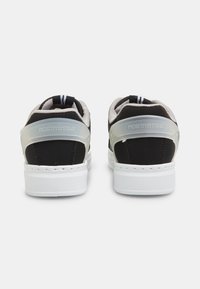 Sneaker neri e grigi con un tallone traslucido e suola bianca. Presentano un dettaglio con il marchio sul tallone e accenti in tessuto a righe.