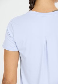 Lichtblauwe T-shirt met korte mouwen, een eenvoudig ontwerp, zachte textuur en een plooi detail in het midden van de rug.