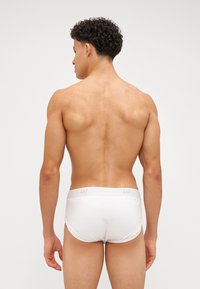 Slip bianchi in stile boxer con branding grigio "GAP" sull'elastico, in tessuto morbido, design aderente e una texture liscia.
