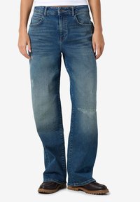 Baggy blauwe denim jeans met vervaagde delen, vijf zakken en een ritssluiting. Licht versleten textuur en recht gesneden pijpen.