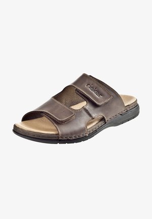 Bruine leren slippersandalen met een verstelbare klittenbandsluiting, gestructureerde zijpanelen, een gevoerd voetbed en een duurzame rubberen zool. Rieker-logo zichtbaar.