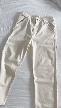 Witte denimbroek met een rechte snit, voorzien van twee voorzakken, een metalen knoopsluiting en zichtbare stiksels langs de naden.