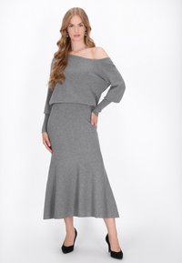 Set tricotat gri, format din două piese, care include un top off-shoulder și o fustă flared, de lungime până la genunchi. Țesătura are o textură moale și un design fără cusături.