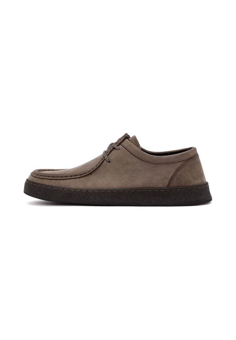 Chaussure en cuir marron avec un profil bas, un bout rond et une épaisse semelle en caoutchouc noir. Présente des coutures minimales et deux œillets pour les lacets.