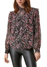 Black sheer blouse with pink and red abstract pattern, ruffled neckline and sleeves, button-down front, paired with black pants.