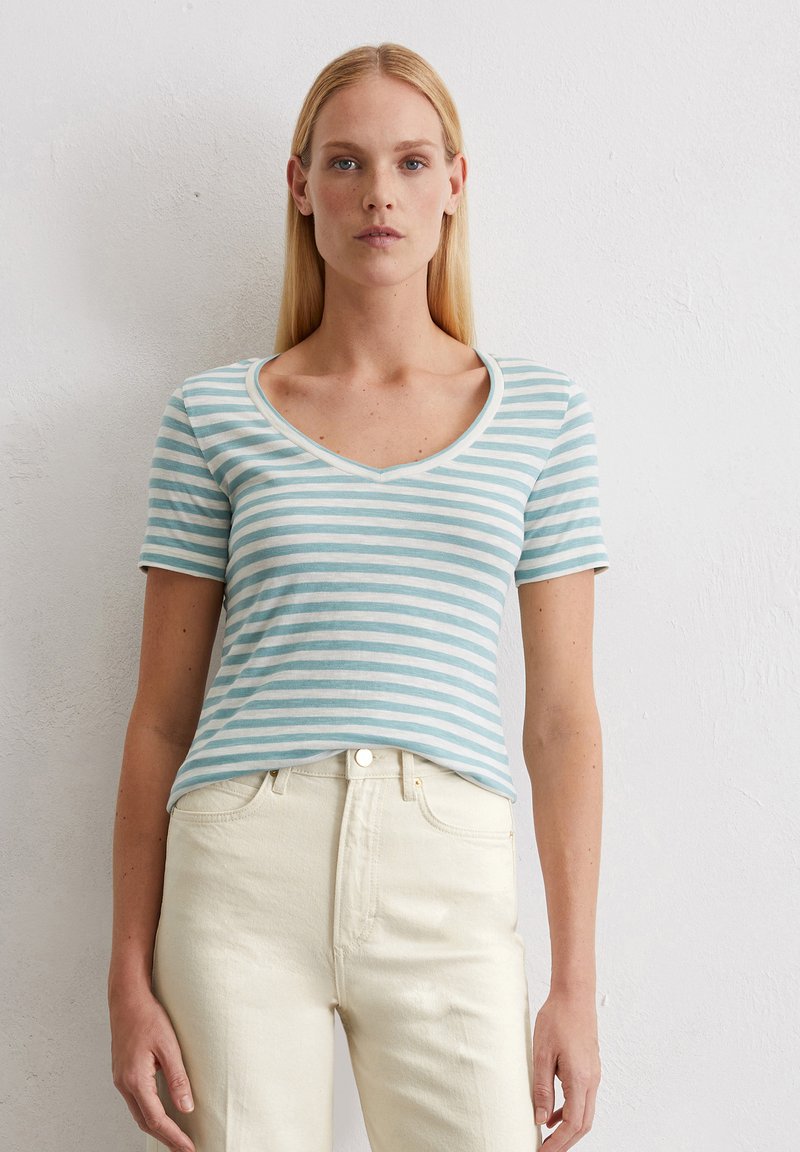 T-shirt a righe a maniche corte in cotone azzurro chiaro e bianco, con scollo a V e vestibilità rilassata, abbinato a jeans bianchi a vita alta.