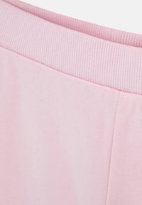 Tissu rose doux avec une large ceinture élastique côtelée cousue à un matériau lisse, montrant la texture du vêtement et les détails de la couture.