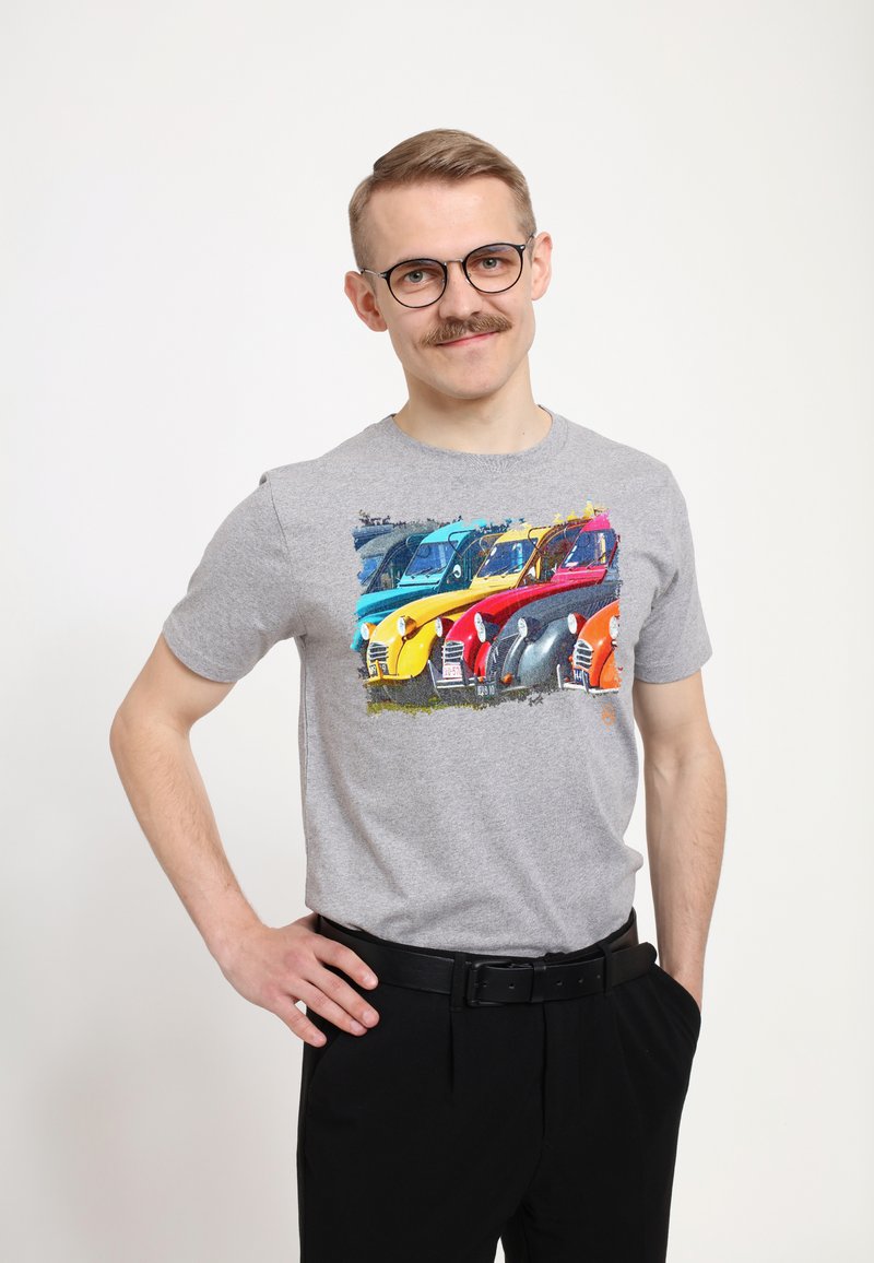 Grå bomulds t-shirt med et farverigt grafisk design af vintage biler i blå, gul, rød og orange. Mændenes bukser er sorte.