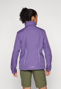 Purple waterproof jacket with a high collar, featuring white accents and elastic cuffs. Worn over olive green shorts, showcasing outdoor design.