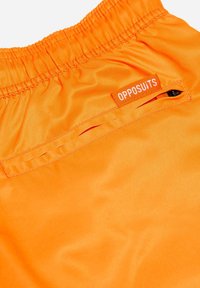 Oranžinės maudymosi šortai su elastinga juosta ir užtrauktuku kišenėje. Pridėta maža etiketė su užrašu "OPPOSUITS", siuvinėta šalia juosmens.