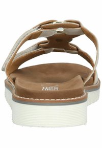 Back view of brown suede sandals with white straps, soft cushioned insole, and a textured white rubber outsole. Features a round metal accent.