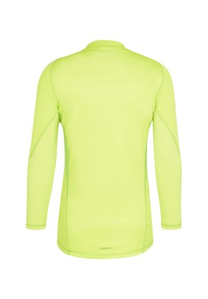 Chemise à manches longues de couleur jaune néon vif. Tissu léger et respirant avec une texture lisse. Présente un col rond simple et des manches à poignets.