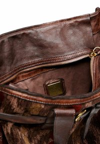 Borsa a tracolla in pelle marrone con zip parzialmente aperta, che mostra l'interno in tessuto e una piccola etichetta dorata all'interno.