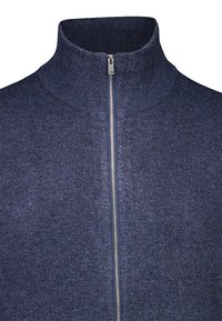 Mörkblå stickad tröja med hög krage och silverfärgad dragkedja framtill, visad från bröstet och uppåt mot en vit bakgrund.