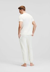 Lichtgekleurde katoenen t-shirt en bijpassende joggingbroek. De outfit heeft gebreide stof, een ontspannen pasvorm en elastische boorden bij de enkels.