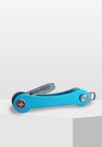 Blå multifunktionell nyckelhållare med matt yta, silverdetaljer och en schweizisk korssymbol. Har en svängbar design för enkel åtkomst till nycklar.