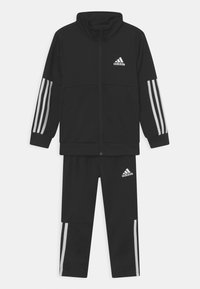 Zwart trainingspak bestaande uit een jack met ritssluiting en hoge kraag, en drie witte strepen op de mouwen, gecombineerd met bijpassende broek.