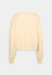 Felpa cropped in morbido tessuto beige, con maniche lunghe, scollatura rotonda e un design semplice senza motivi visibili.