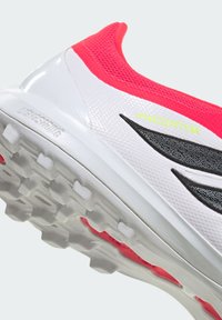 Urheilukengät valkoisina ja neonpinkkeinä, joissa on teksturoidut päälliset, mustat yksityiskohdat, pehmustettu pohja ja kuvioitu muotoilu.