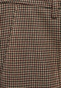 Hahnentrittstoff in Burgunderrot, Schwarz und Beige. Ausgeprägtes kariertes Muster mit strukturierter Oberfläche. Geeignet für maßgeschneiderte Kleidung.