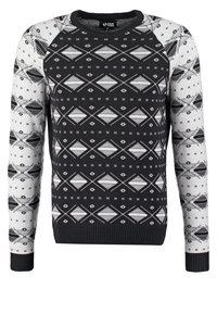 Pull à motif noir et blanc avec un col rond, présentant des dessins géométriques et des poignets côtelés. Confectionné en tissu tricoté.