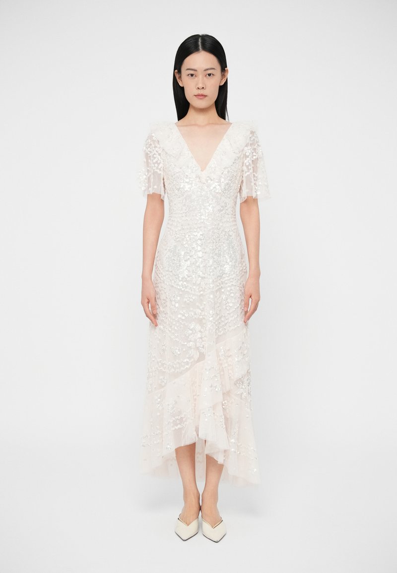 Rochie bej deschis cu mâneci scurte evazate, decolteu în V și ornamente strălucitoare. Prezintă volane stratificate și tiv până la genunchi.