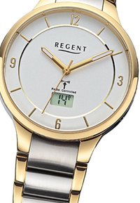 Montre analogique dorée avec cadran blanc, bracelet en métal et affichage numérique. Les caractéristiques comprennent de grands index horaires et une synchronisation horaire radio. 
