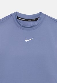 Nike Pro idretts skjorte, kortermet, lys blå, glatt tekstur, har en hvit logo på brystet og en ribbet kragedetalj.