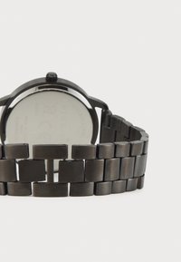 Black metal wristwatch with a brushed finish, featuring a solid link bracelet and a round case. The back is smooth and reflective.