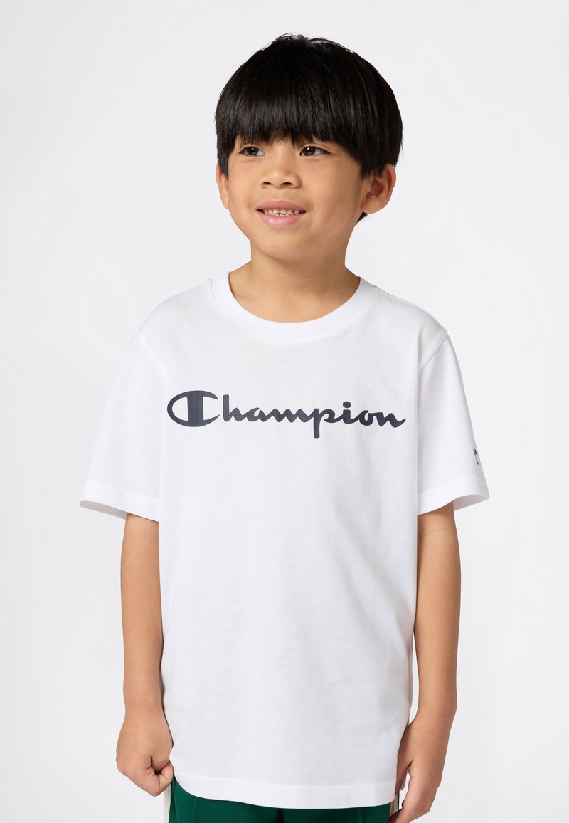 Bílá bavlněná tričko s velkým námořnickým logem "Champion" na přední straně. Krátké rukávy a kulatý výstřih s uvolněným střihem.