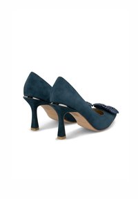 Pumps in suede blu scuro con punta affusolata e tacco di 5 cm, caratterizzati da un decorativo ornamento in cristallo sulla parte frontale.