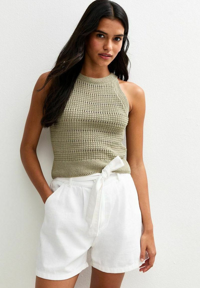 Haut halter en tricot olive avec un motif texturé, associé à un short en lin blanc avec un détail de taille nouée et des poches latérales.