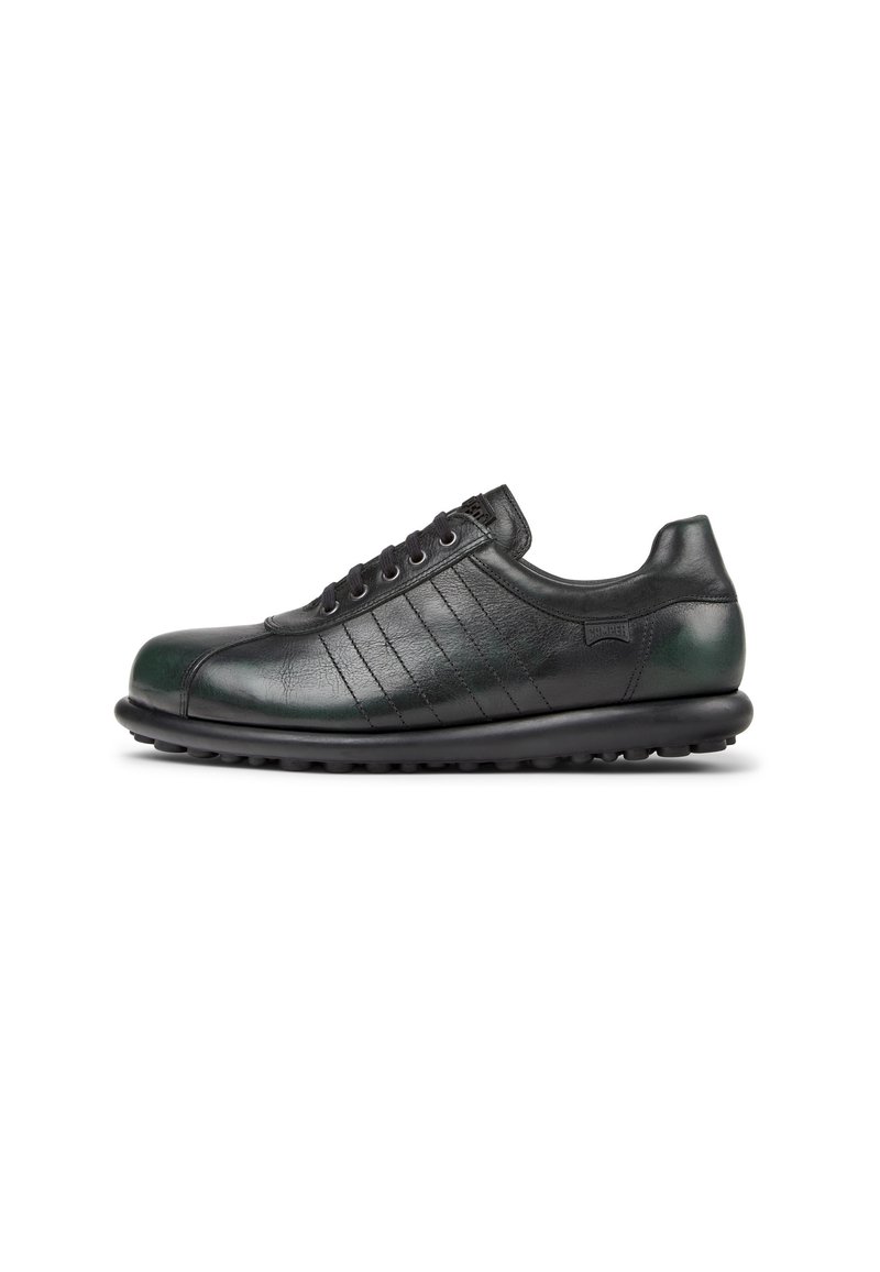 Scarpa in pelle nera con punta arrotondata, pannelli laterali testurizzati e cinque occhielli. Presenta una suola in gomma con piccole scanalature per garantire la trazione.
